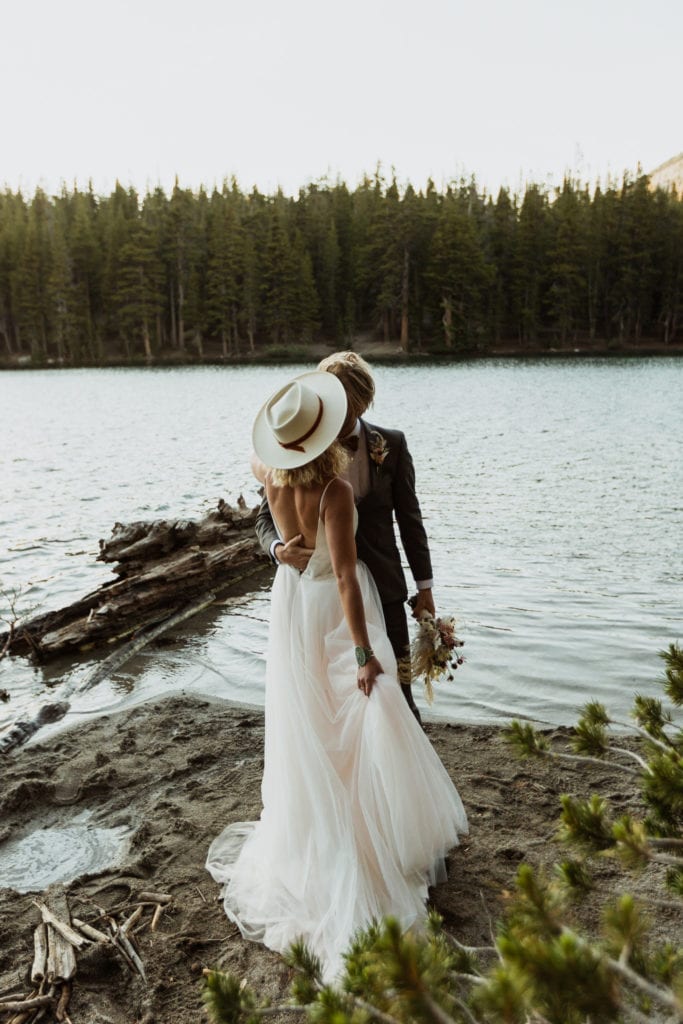 A brride and groom standing and hugging at the edge of McLeod Lake