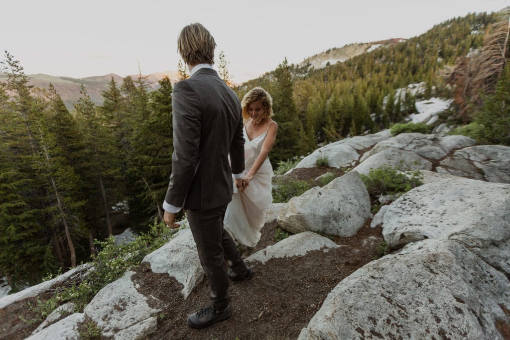 Tyler helps Haylee climb over rocks after eloping in Mammoth Lakes. 