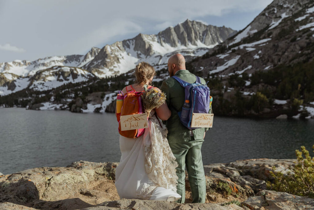 A couple stands at a lake out of Bishop, CA with Just Married signs after tying the knot. 