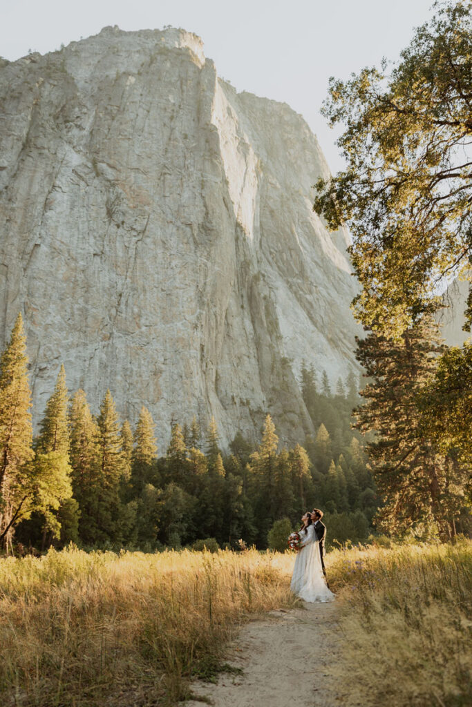 A newlywed couple stands in the middle of a trail on their wedding day in Yosemite National Park.