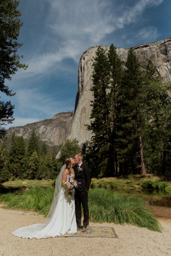 A couple kisses for the first time on their wedding day on Cathedral Beach in Yosemite National Park. 